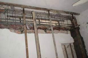 在需拆除的墙体的两侧,设置钢管支撑立柱,加上横梁,下加垫板,将墙体上